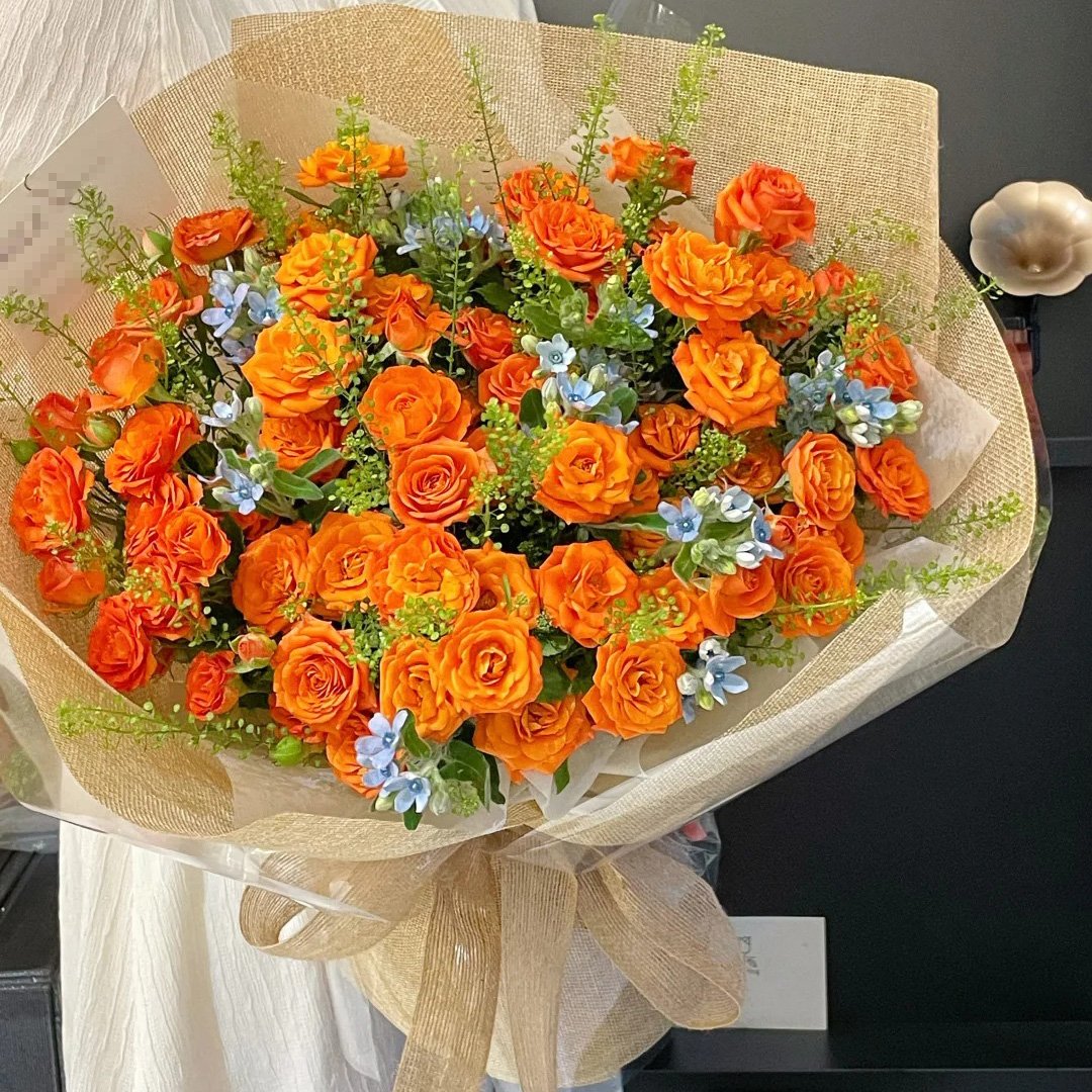 橙色梦想-橙芭比多头玫瑰花19枝（花朵至少50朵）或相似花型橙色花朵，绿铃草饱满，蓝星花；如图包装（包装纸可能使用同色其它材质替代）